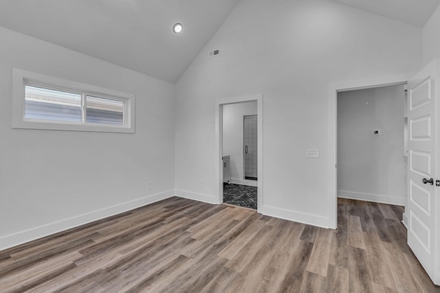 unfurnished bedroom featuring hardwood / wood-style flooring, ensuite bathroom, and high vaulted ceiling