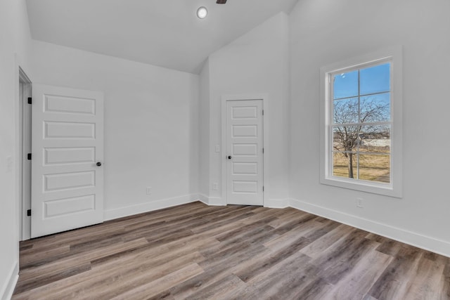 empty room with hardwood / wood-style floors and high vaulted ceiling