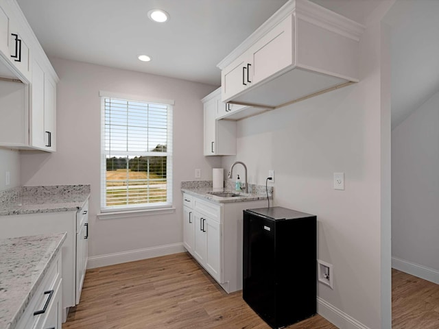 kitchen featuring white cabinets, sink, light hardwood / wood-style flooring, fridge, and light stone counters