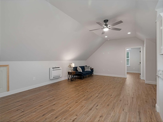 additional living space with ceiling fan, light hardwood / wood-style floors, vaulted ceiling, and heating unit