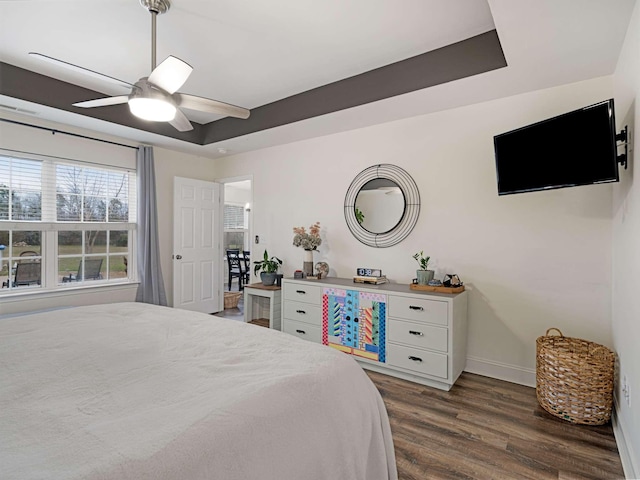 bedroom featuring a tray ceiling, ceiling fan, and dark hardwood / wood-style flooring