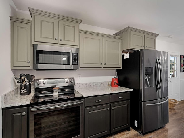 kitchen with stainless steel appliances, light stone counters, hardwood / wood-style flooring, and gray cabinetry