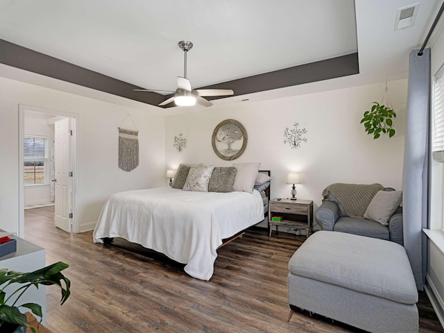 bedroom with a tray ceiling, ceiling fan, and dark hardwood / wood-style floors