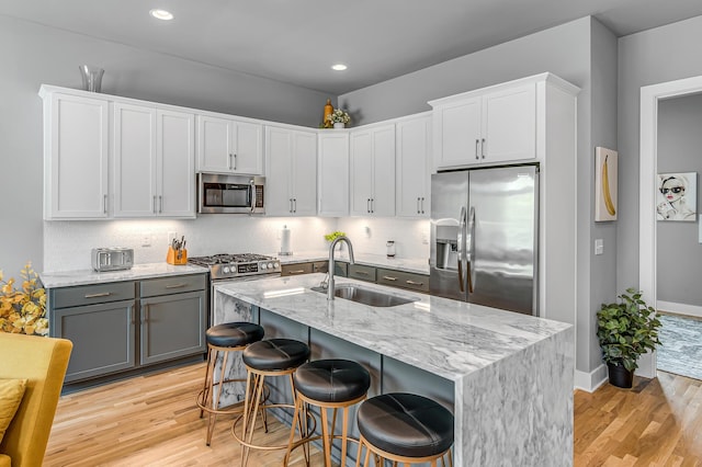 kitchen featuring a center island with sink, a kitchen breakfast bar, sink, and appliances with stainless steel finishes