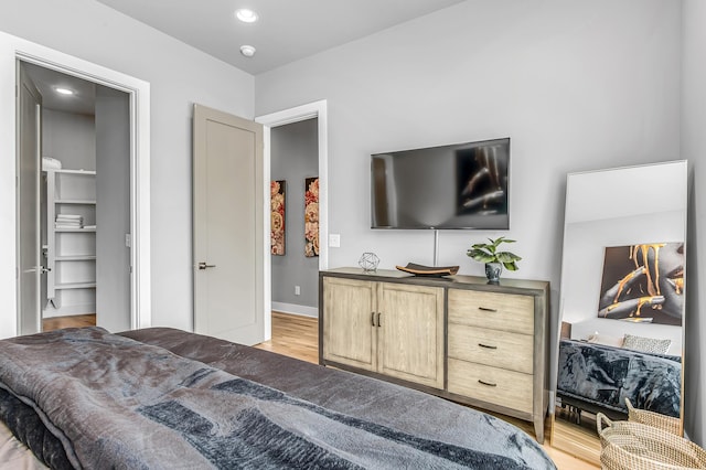 bedroom with light wood-type flooring and a walk in closet