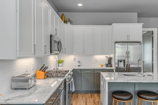 kitchen with a breakfast bar area, backsplash, sink, and appliances with stainless steel finishes