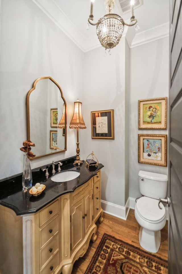 bathroom featuring wood-type flooring, vanity, an inviting chandelier, and crown molding