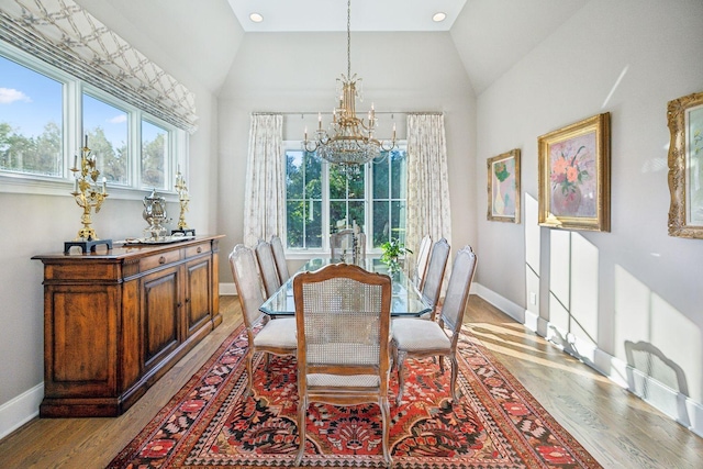 dining space featuring a chandelier, vaulted ceiling, and light hardwood / wood-style floors