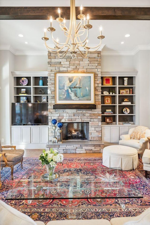 living room featuring a stone fireplace, crown molding, hardwood / wood-style floors, and an inviting chandelier