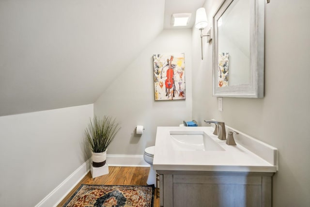 bathroom featuring vanity, toilet, wood-type flooring, and vaulted ceiling