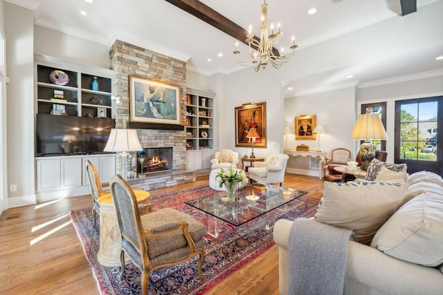 living room with an inviting chandelier, a stone fireplace, crown molding, built in shelves, and light hardwood / wood-style floors