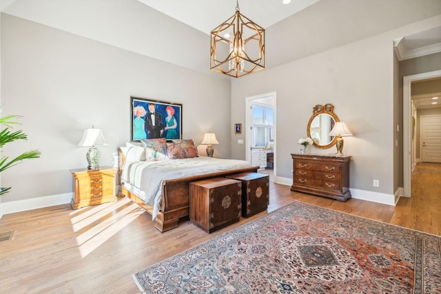 bedroom with hardwood / wood-style floors, ensuite bathroom, and an inviting chandelier