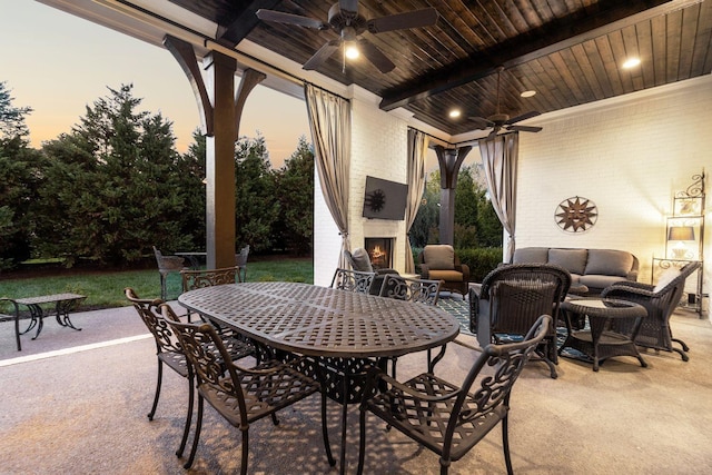 patio terrace at dusk featuring an outdoor living space with a fireplace and ceiling fan