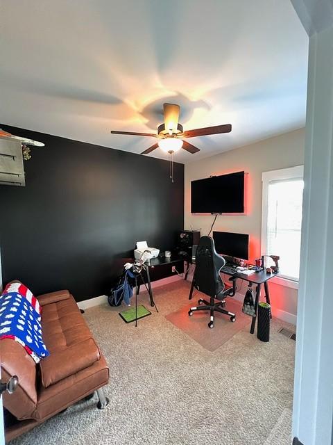 carpeted office space with ceiling fan and a wall mounted AC