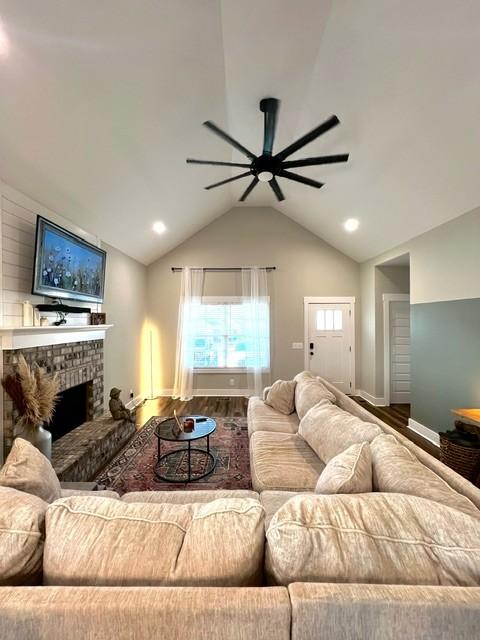 living room with ceiling fan, hardwood / wood-style floors, a fireplace, and lofted ceiling