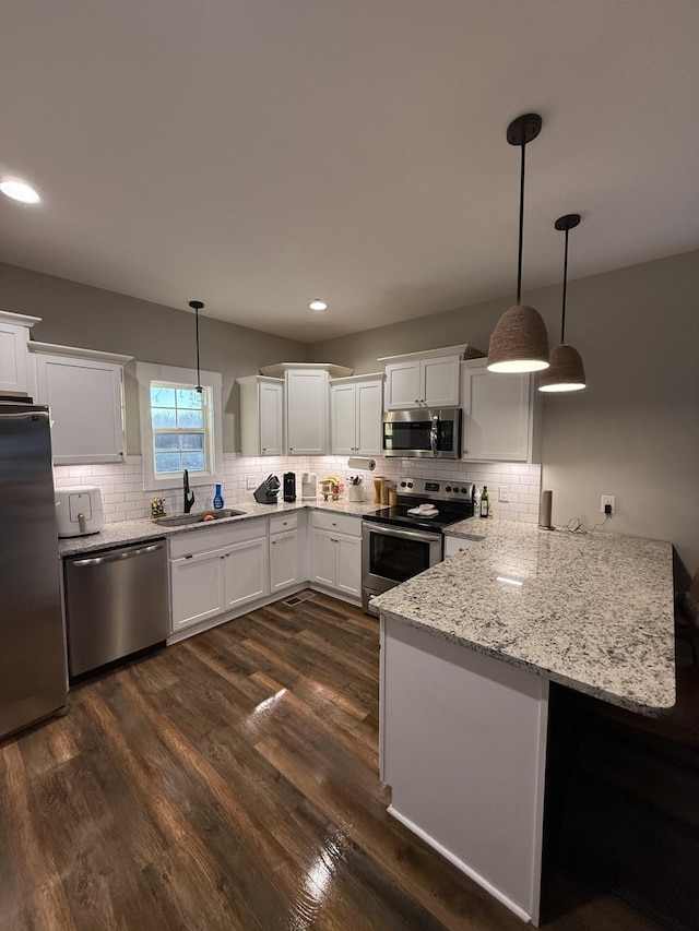 kitchen with sink, white cabinets, hanging light fixtures, and stainless steel appliances