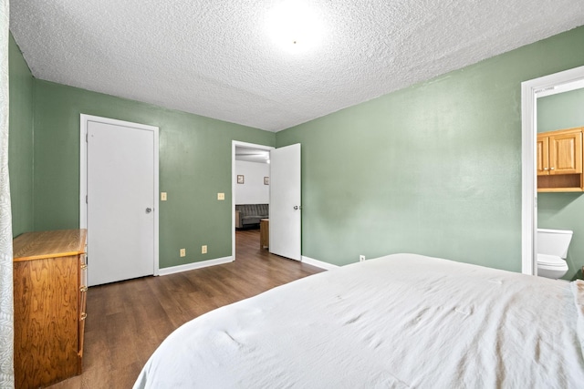 bedroom featuring ensuite bath, dark wood-type flooring, and a textured ceiling