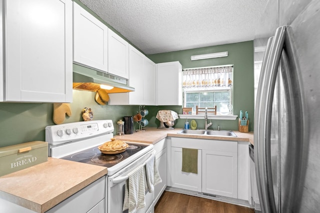 kitchen with white electric range oven, white cabinetry, sink, and stainless steel refrigerator