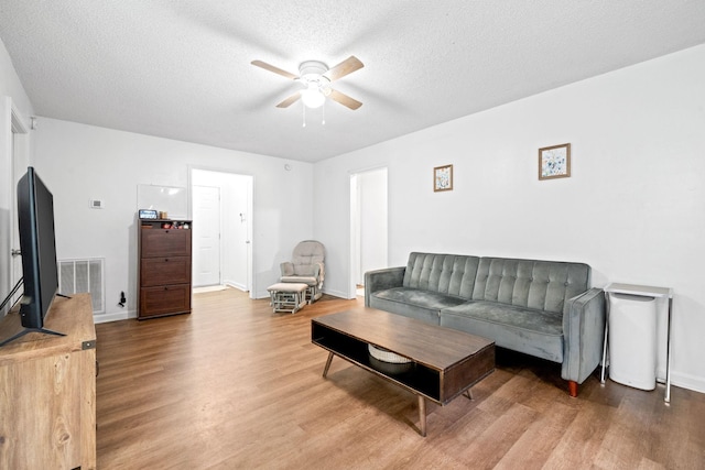 living room with a textured ceiling, light hardwood / wood-style flooring, and ceiling fan