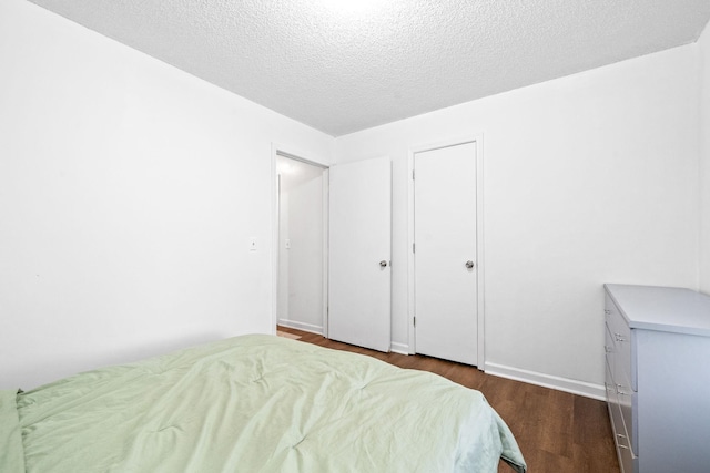 bedroom with dark hardwood / wood-style flooring and a textured ceiling