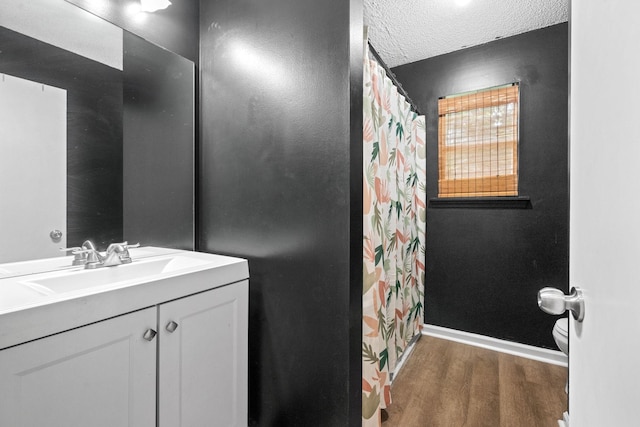 bathroom featuring vanity, wood-type flooring, a textured ceiling, and toilet