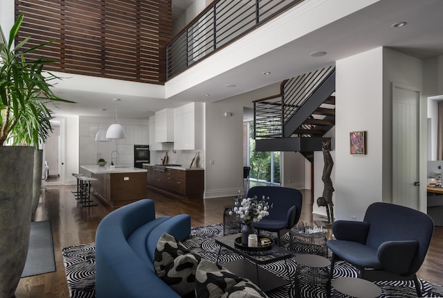 living room with dark hardwood / wood-style flooring, a towering ceiling, and sink