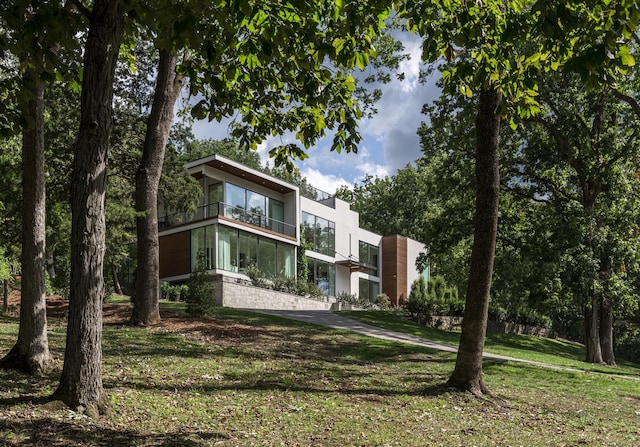 contemporary home featuring a balcony and a front lawn