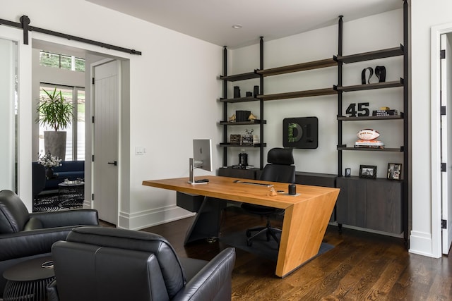 home office with a barn door and dark hardwood / wood-style flooring