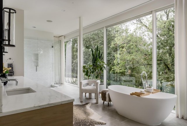 bathroom with tile patterned flooring, vanity, separate shower and tub, and a wealth of natural light