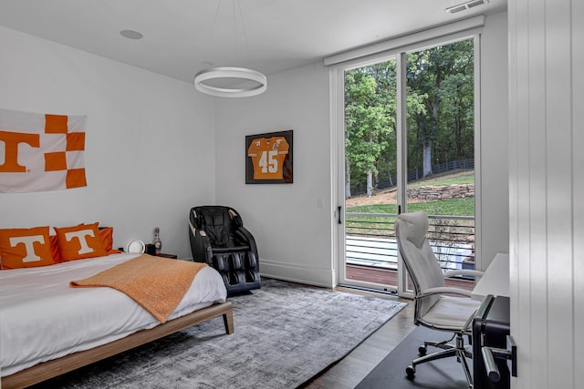 bedroom featuring access to exterior, wood-type flooring, and a wall of windows