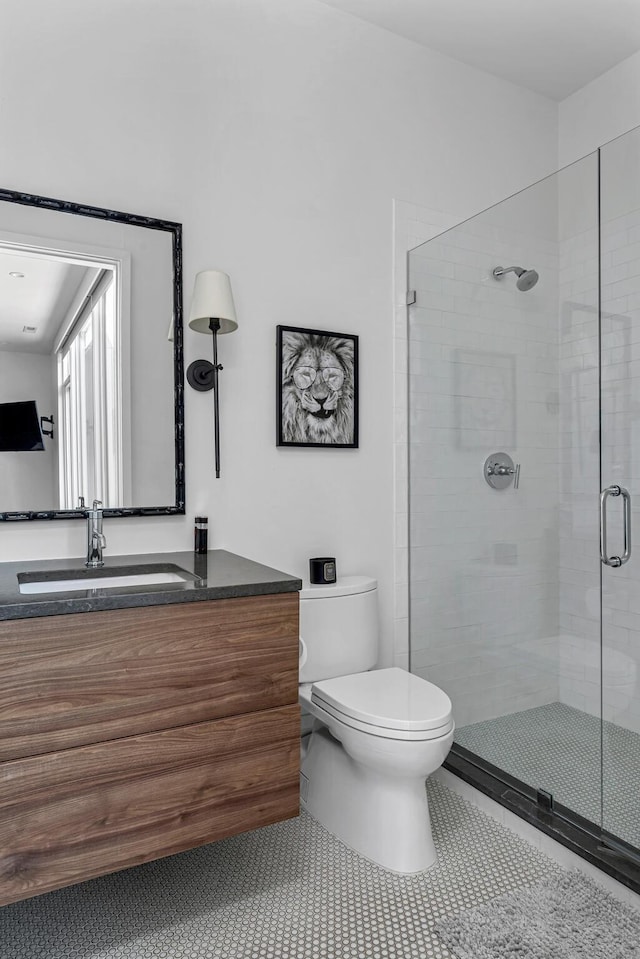 bathroom with tile patterned flooring, vanity, toilet, and walk in shower