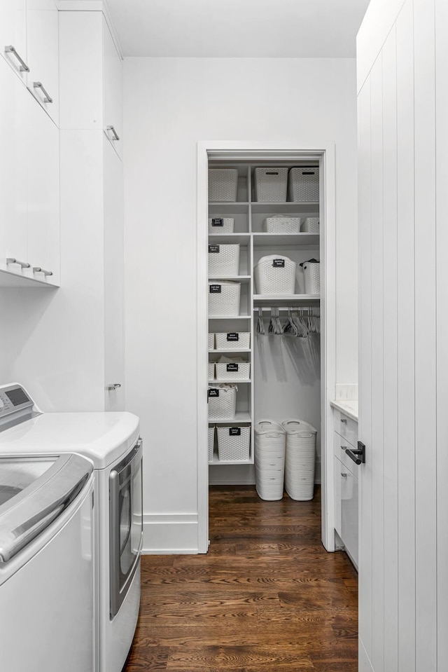 washroom with cabinets, separate washer and dryer, and dark wood-type flooring