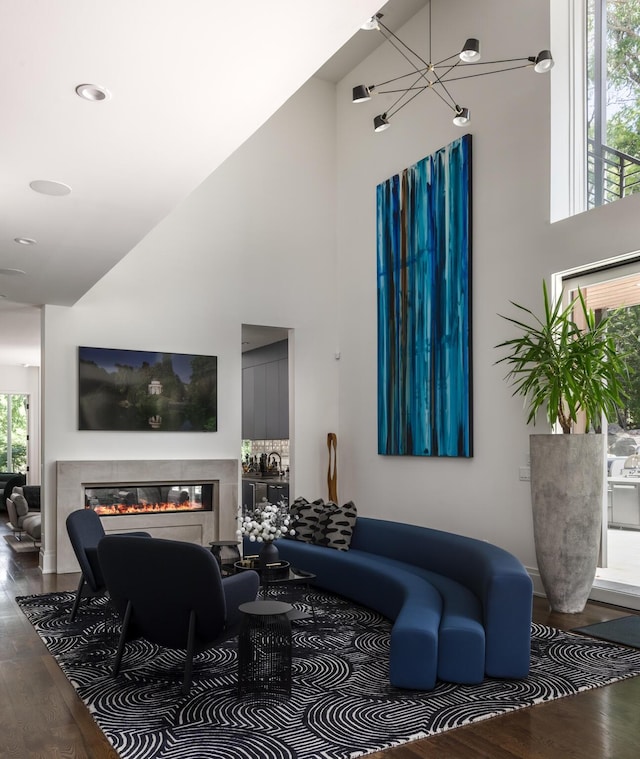 living room with hardwood / wood-style floors, a notable chandelier, and high vaulted ceiling