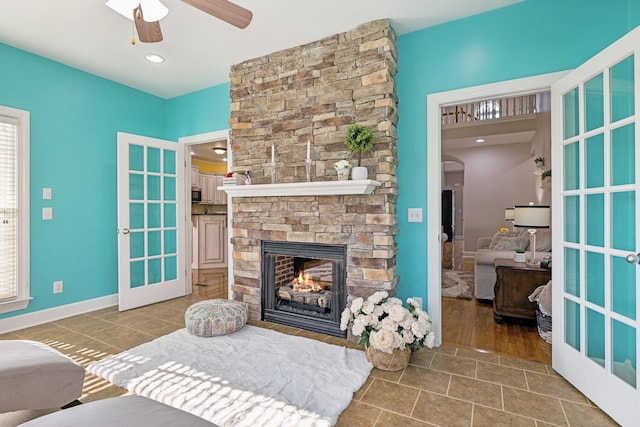 tiled living area with a ceiling fan, arched walkways, a healthy amount of sunlight, and a fireplace