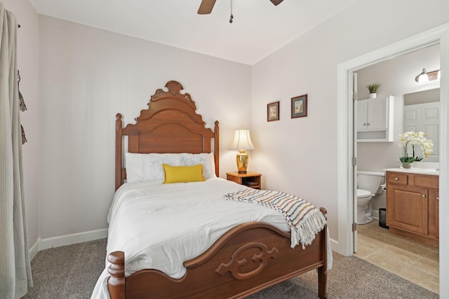 bedroom with baseboards, ensuite bathroom, a ceiling fan, and light colored carpet