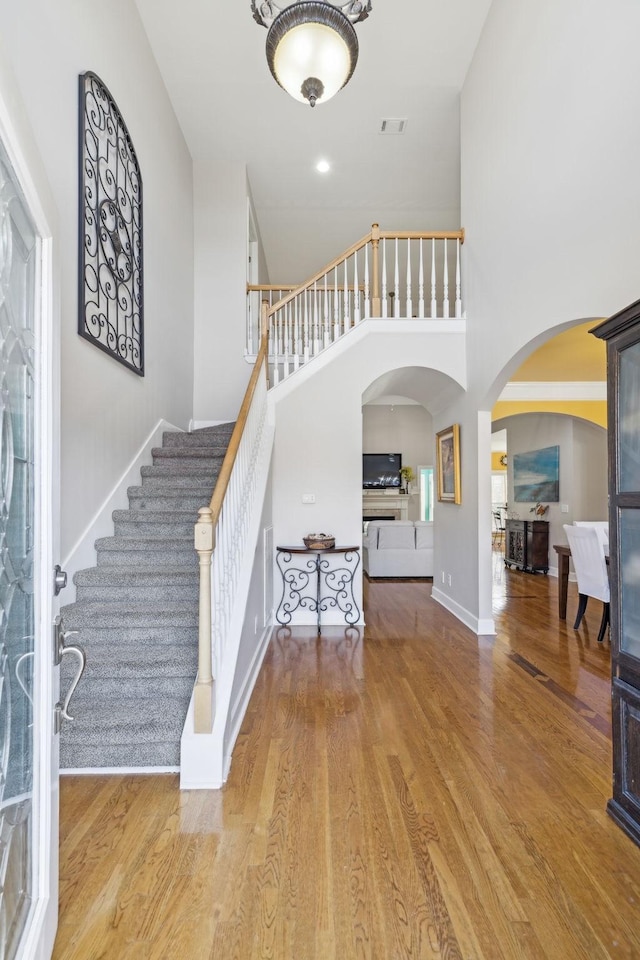 entrance foyer with hardwood / wood-style floors and a towering ceiling