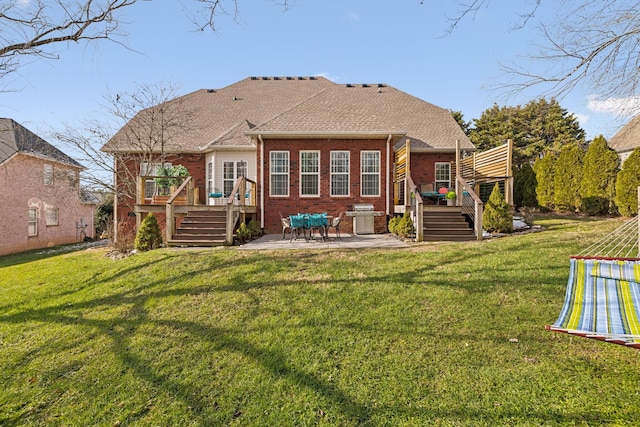 rear view of house featuring brick siding, a patio, a wooden deck, and stairs