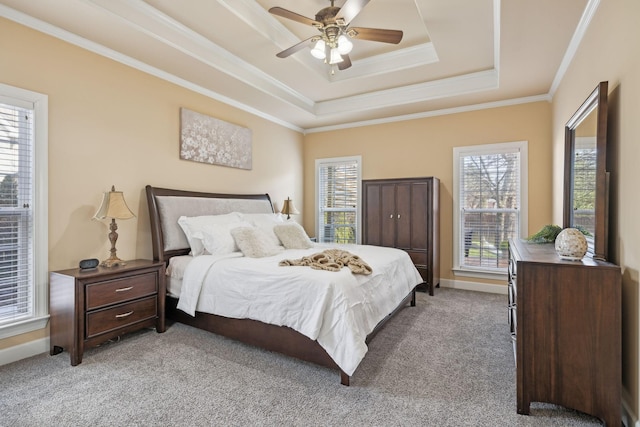 bedroom with ornamental molding, a tray ceiling, light carpet, and baseboards