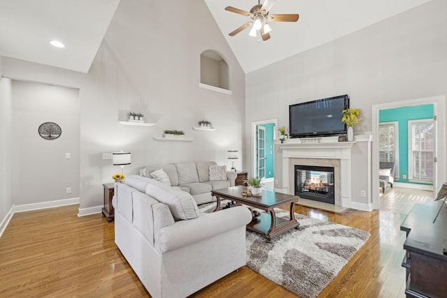 living room with a multi sided fireplace, baseboards, and wood finished floors