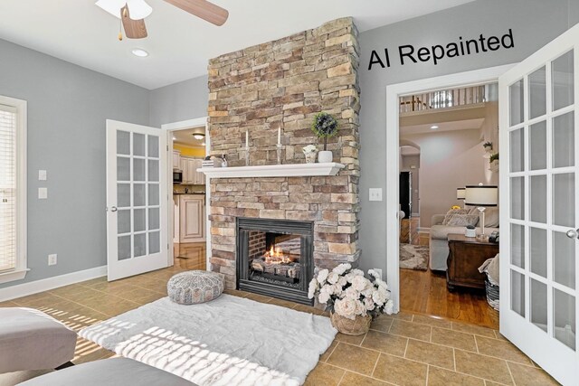 living room featuring plenty of natural light, a fireplace, arched walkways, and a ceiling fan