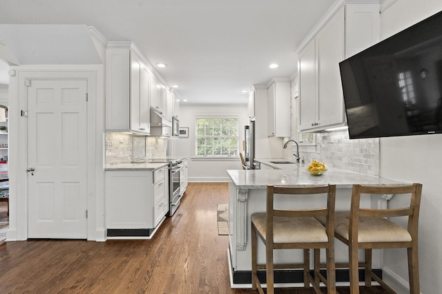 kitchen featuring a kitchen breakfast bar, white cabinetry, sink, and stainless steel appliances