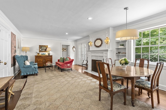 dining area featuring a fireplace, wood-type flooring, and ornamental molding