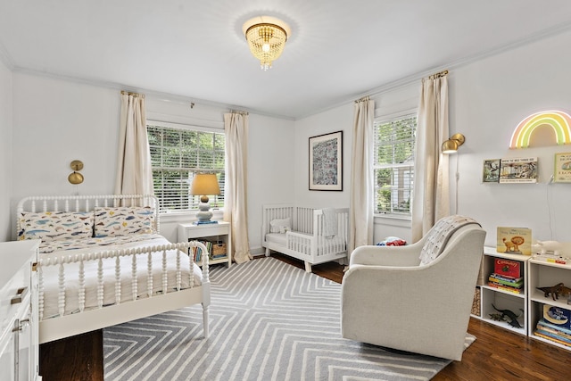 bedroom with multiple windows, dark hardwood / wood-style floors, and ornamental molding