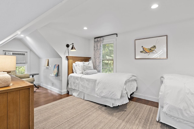 bedroom with hardwood / wood-style flooring, an AC wall unit, and multiple windows