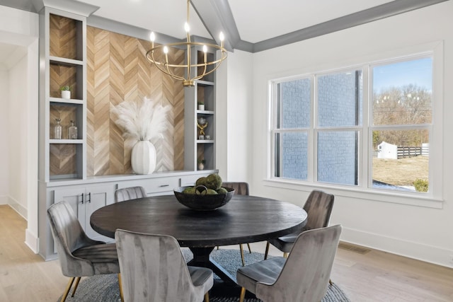 dining space featuring crown molding, a chandelier, built in shelves, and light wood-type flooring