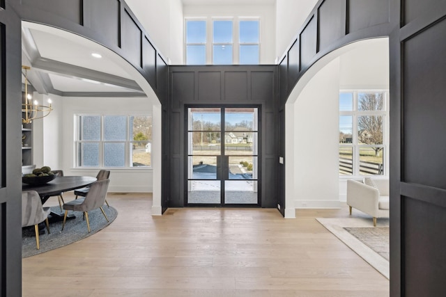 entryway featuring a towering ceiling, light hardwood / wood-style flooring, and a notable chandelier