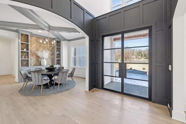 dining space featuring a healthy amount of sunlight, light hardwood / wood-style floors, built in features, and a notable chandelier