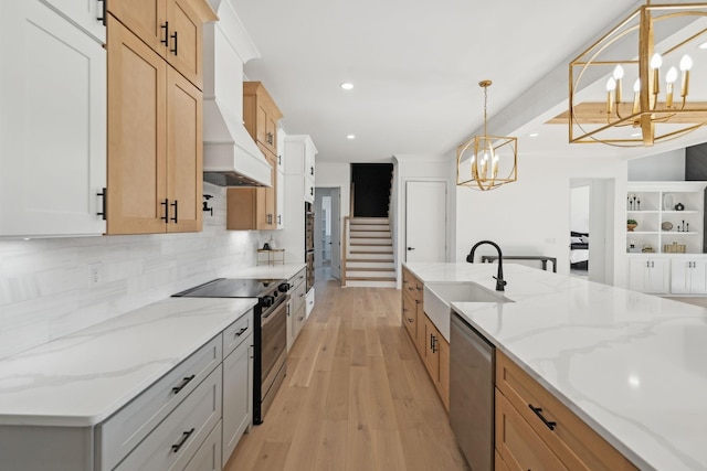 kitchen with sink, white cabinetry, a chandelier, pendant lighting, and stainless steel appliances