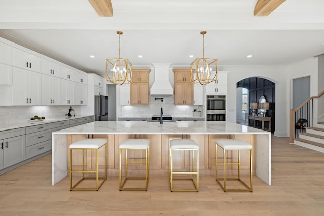 kitchen with a spacious island, hanging light fixtures, and custom exhaust hood