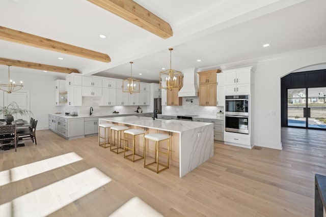 kitchen with custom exhaust hood, a large island, pendant lighting, and white cabinets